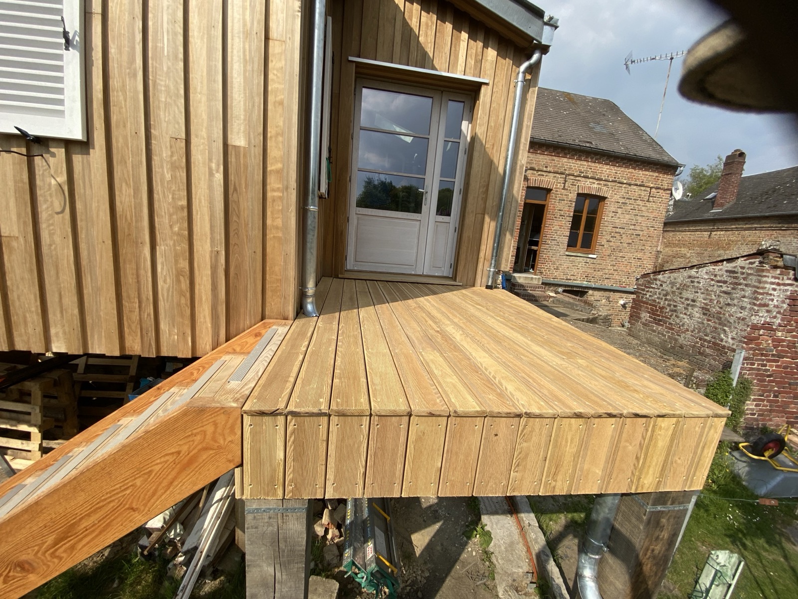 Extension en bardage bois vertical clair en surplomb d'une cour ancienne — Dagicour Seine-Maritime