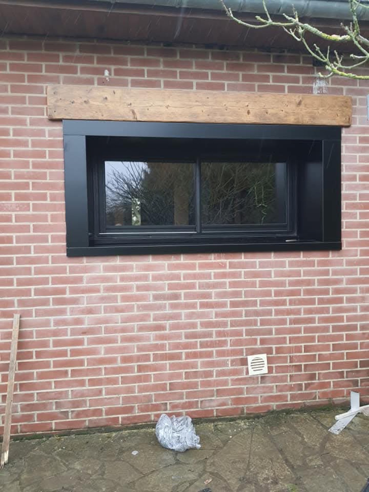 Fenêtre coulissante aluminium noir sur façade en briques rouges, linteau bois — Dagicour Seine-Maritime