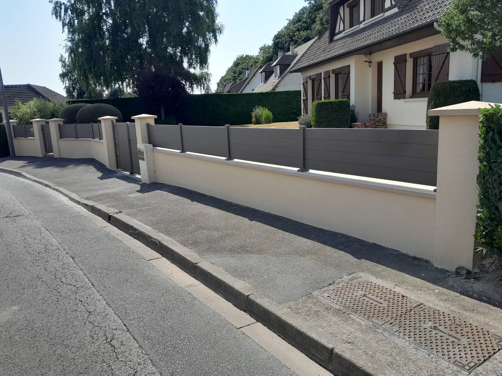 Clôture aluminium grise sur muret enduit crème en Normandie — réalisation Dagicour