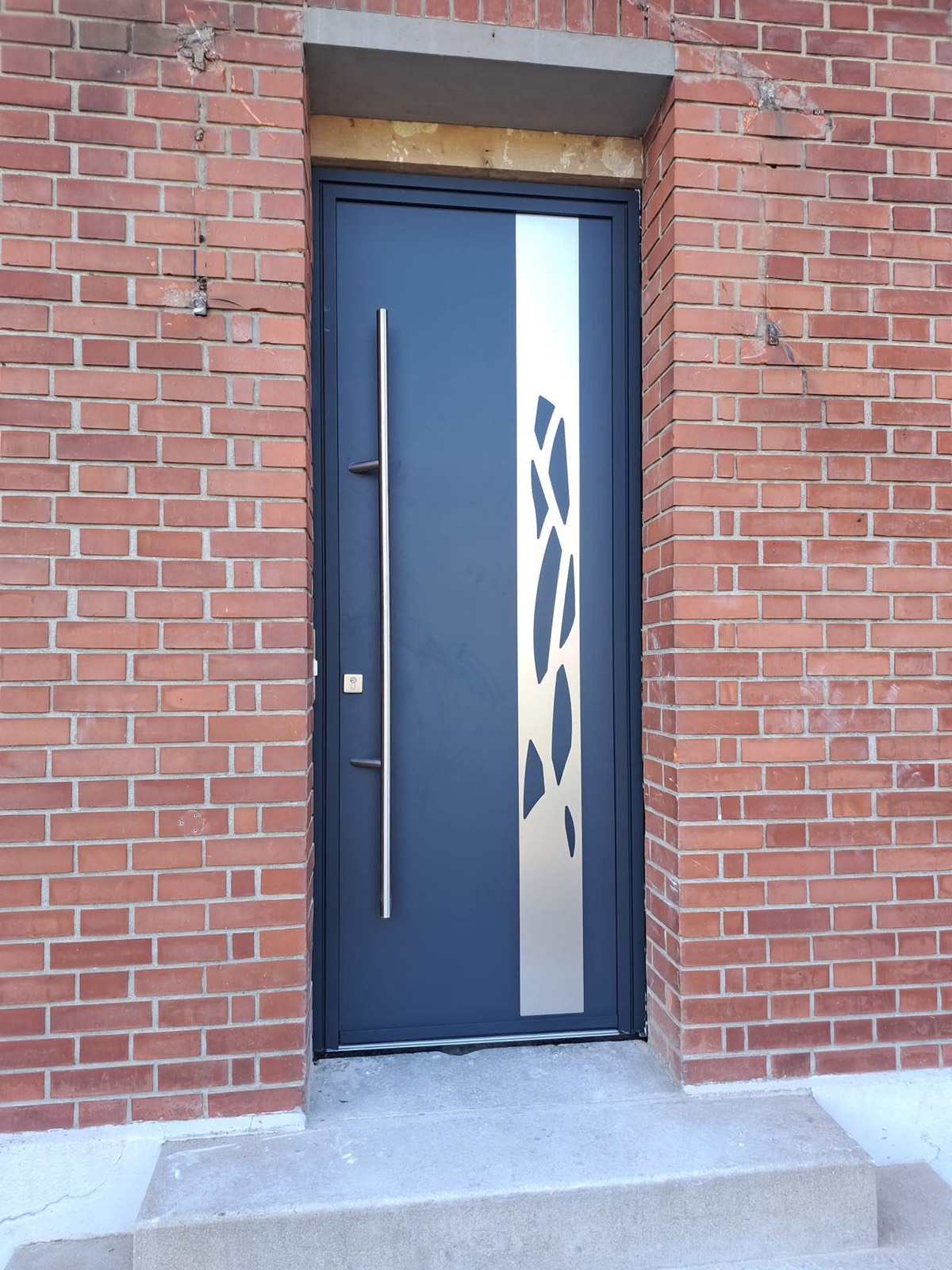 Porte d'entrée aluminium anthracite design contemporain avec motif découpé, sur façade en briques — Dagicour