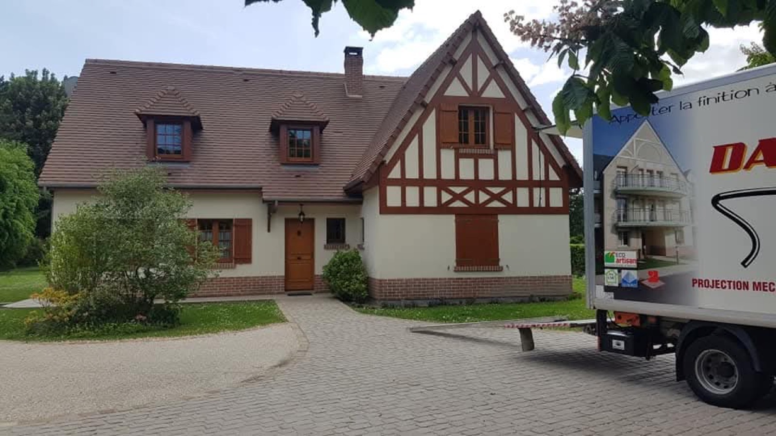 Camion Dagicour Projection devant une maison à colombages fraîchement ravalée en Seine-Maritime