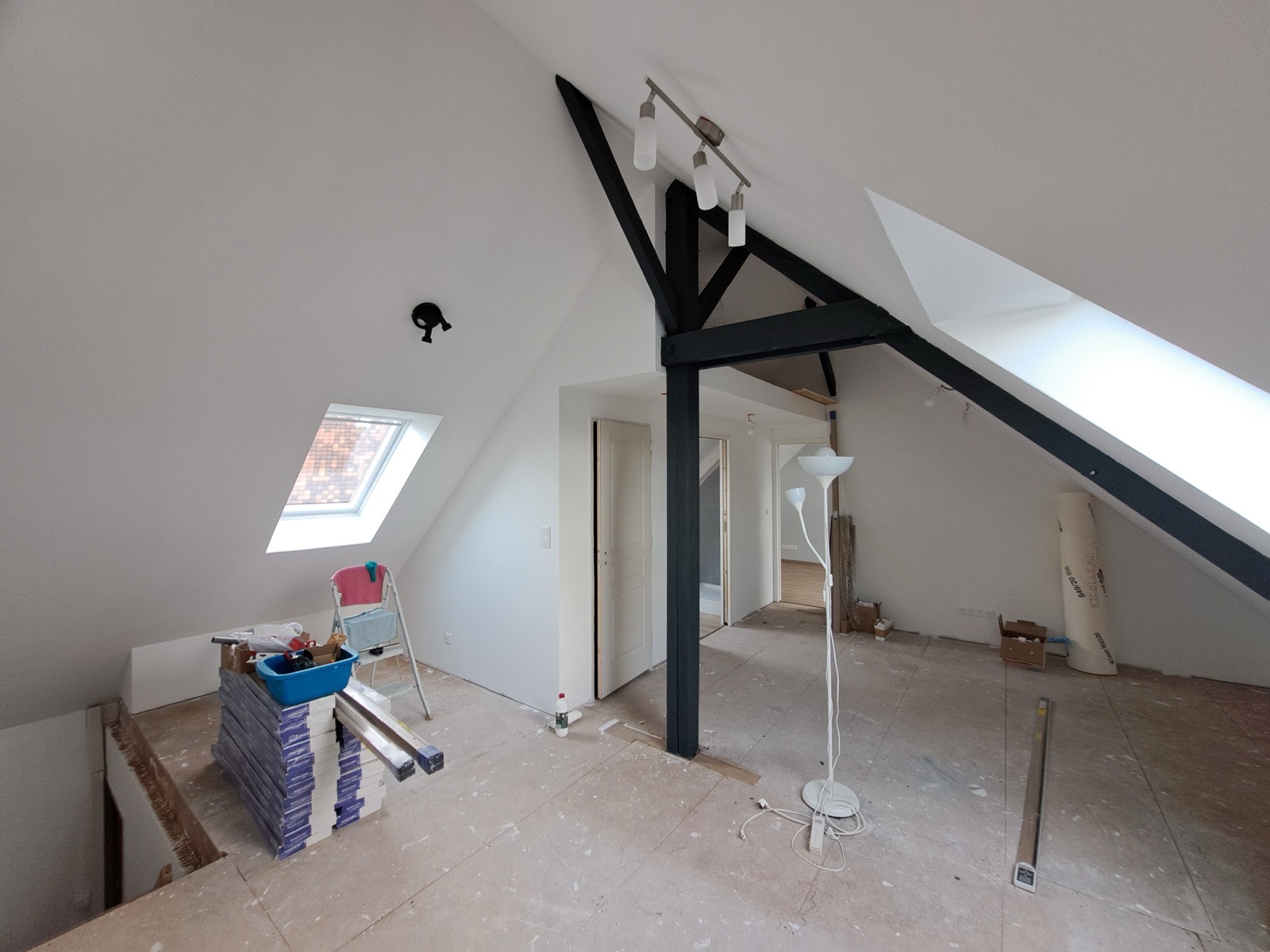 Combles aménagés avec poutre d'ossature noire apparente, velux et parquet, chantier de transformation Dagicour en Seine-Maritime